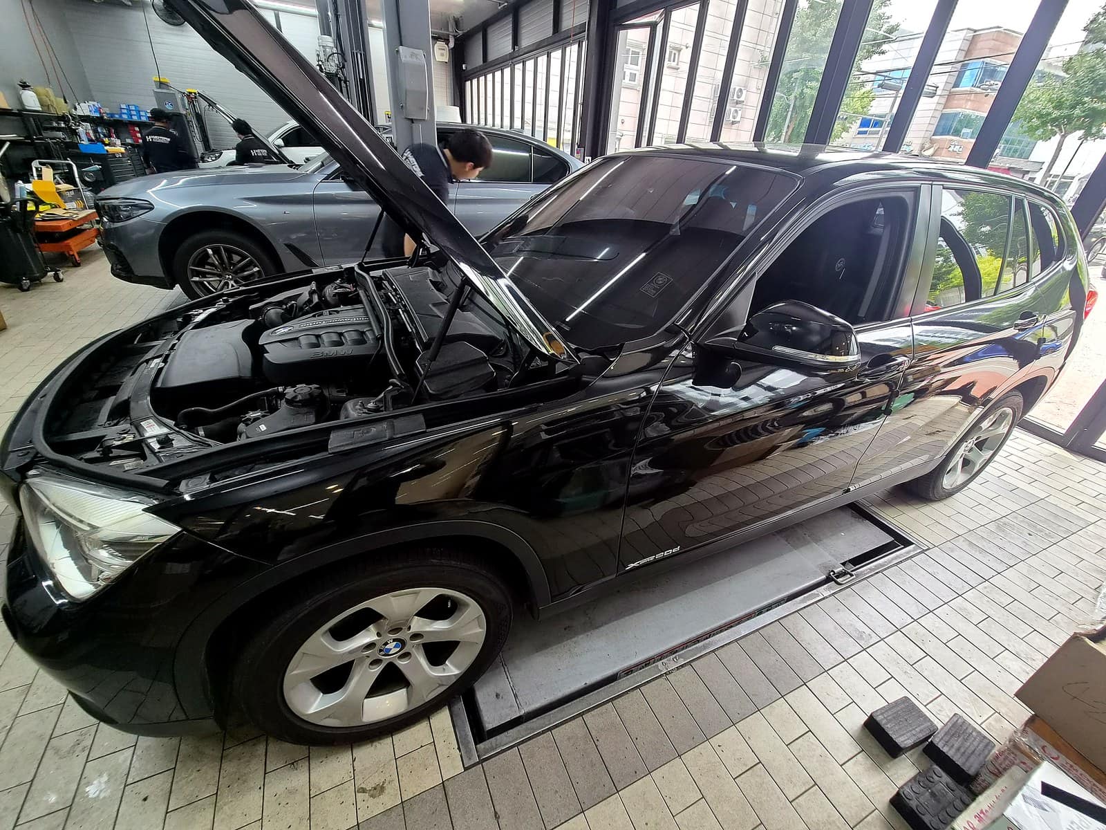 BMW X1 엔진룸을 열어 발전기 위치를 확인하는 모습